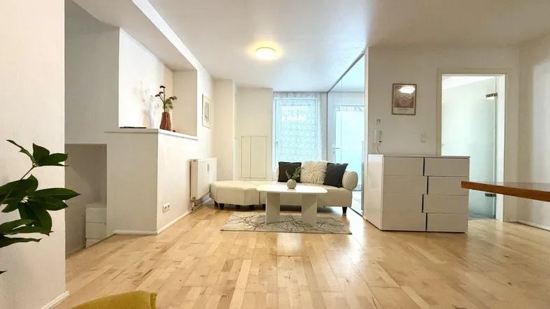 Helles Wohnzimmer mit hellem Holzboden, bequemer Couch und modernem Sideboard.