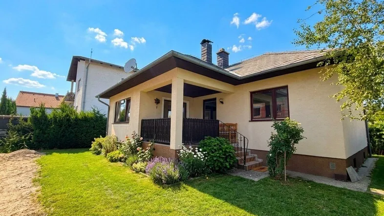 Einladendes Einfamilienhaus mit gepflegtem Vorgarten und sonnigem Rasenbereich unter blauem Himmel.