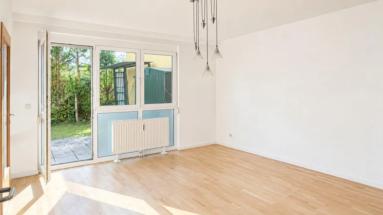 Helles Zimmer mit Holzboden und direktem Zugang zu einer kleinen Terrasse und dem Garten.