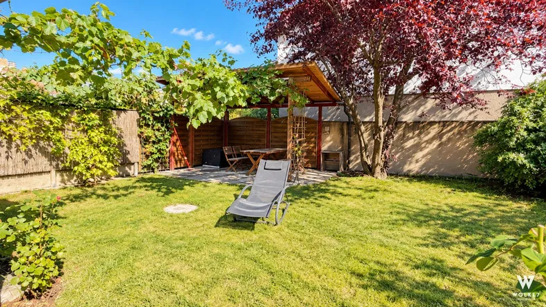 Gepflegter Garten mit Rasenfläche, schattiger Pergola und Liegestuhl für entspannte Stunden im Freien.