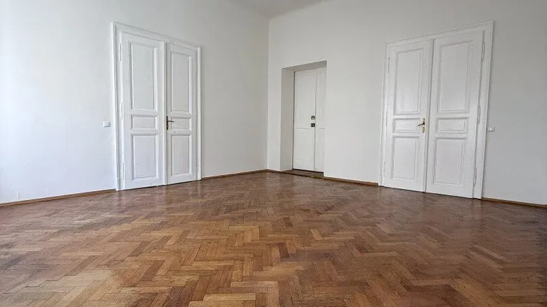 Geräumiges Zimmer mit klassischem Fischgrätparkett und hohen weißen Türen, bereit zur individuellen Gestaltung.