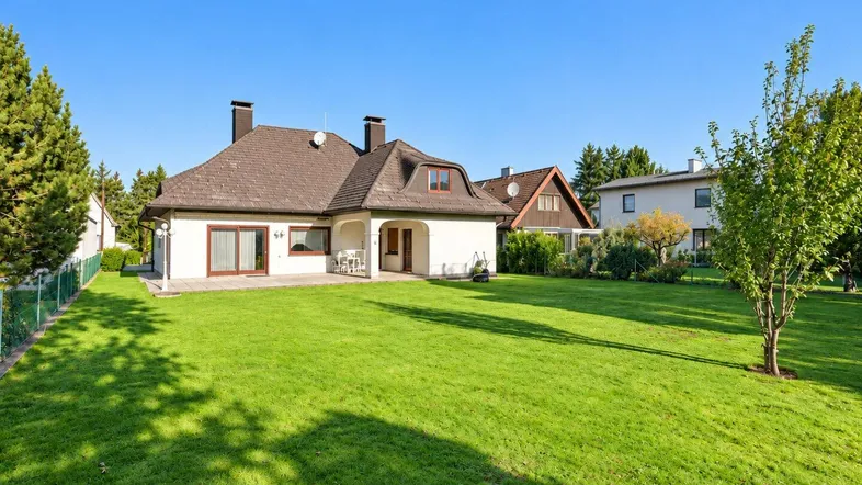 Großer, gepflegter Garten mit weitläufiger Rasenfläche und Blick auf die Rückseite des Hauses.