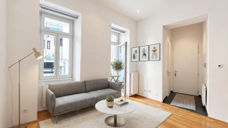 Helles Wohnzimmer mit modernem Sofa, Couchtisch und Zugang zu einem kleinen Balkon.