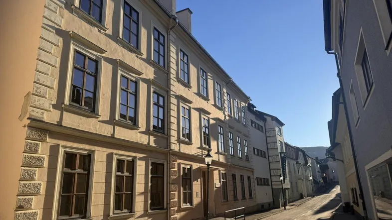 Historische Gebäude entlang einer sonnigen Straße mit traditioneller Architektur und gepflegten Fassaden.