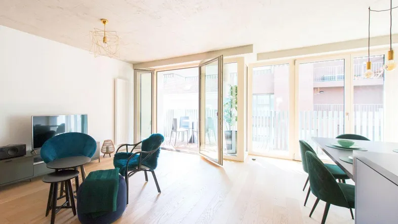 Helles Wohn- und Esszimmer mit Holzboden, modernen Möbeln und Zugang zum Balkon.
