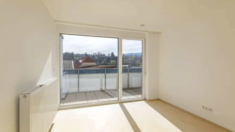 Helles Zimmer mit Zugang zu einem Balkon und Blick auf die Umgebung.
