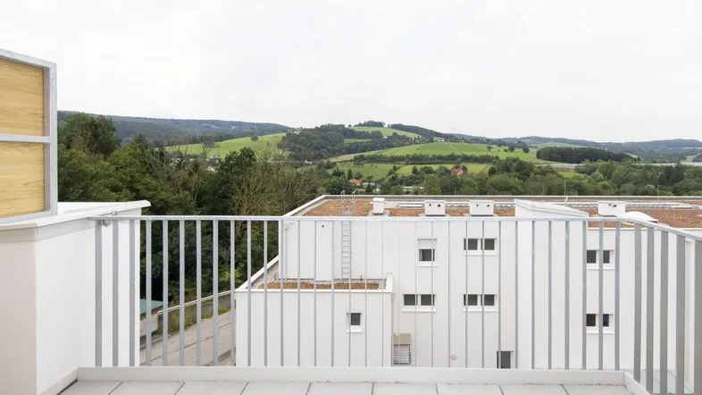 Geräumiger Balkon mit Fliesenboden und weitem Blick über die grüne Landschaft.