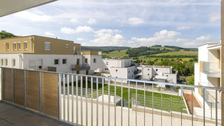 Blick vom Balkon auf die umliegende Hügellandschaft und moderne Wohngebäude.