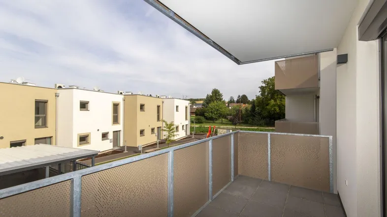 Balkon mit Blick auf die umliegenden Neubauten und Grünflächen der Wohnanlage.