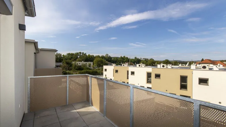 Balkon mit Fliesenboden und Blick auf die umliegenden Gebäude und den Himmel.
