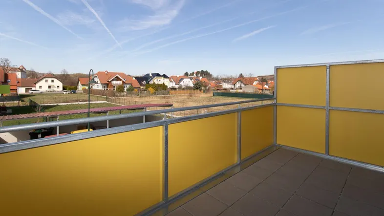 Geräumiger Balkon mit gelber Brüstung und weitem Blick über die umliegende Wohnsiedlung.