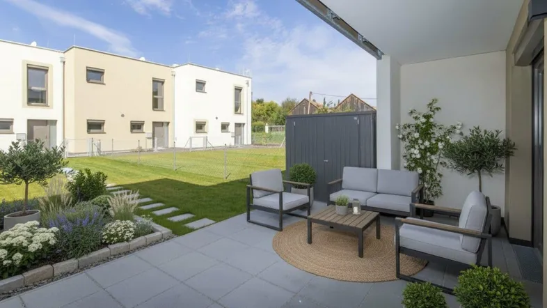 Geräumige Terrasse mit modernen Gartenmöbeln und Blick auf den Gartenbereich des Neubaus.