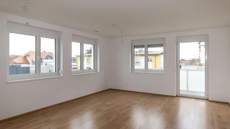Helles und geräumiges Zimmer mit Laminatboden und direktem Zugang zum Balkon.