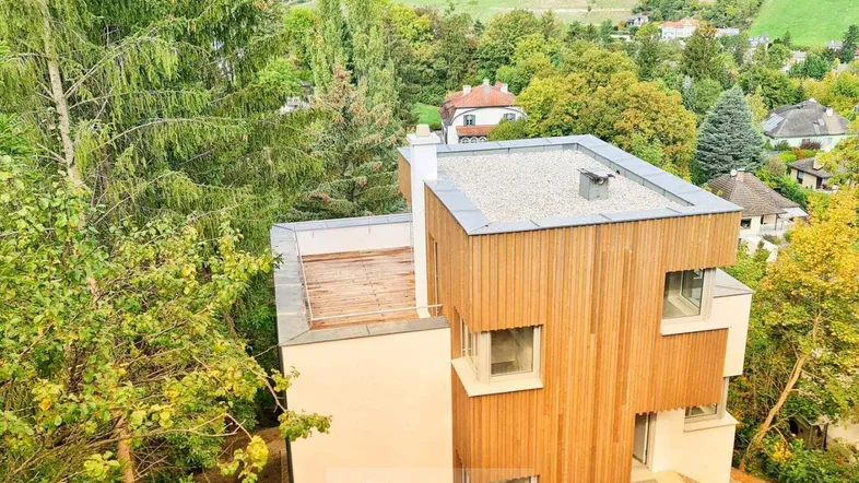 Moderne Architektur des Hauses mit Holzfassade und Flachdach, umgeben von viel Grün.