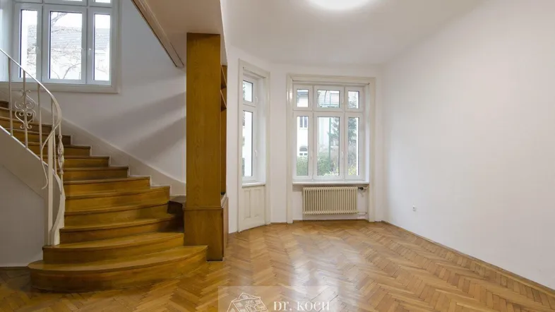 Geräumiger Flur mit eleganter Holztreppe und Fischgrätparkettboden.