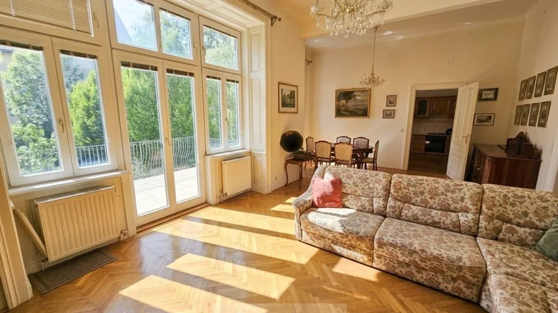 Helles Wohn- und Esszimmer mit Fischgrätparkett, hohen Decken und Zugang zum Balkon.