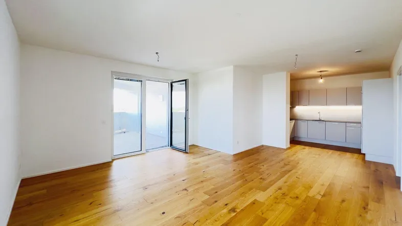 Heller, offener Wohn- und Essbereich mit modernem Holzboden und Zugang zum Balkon.