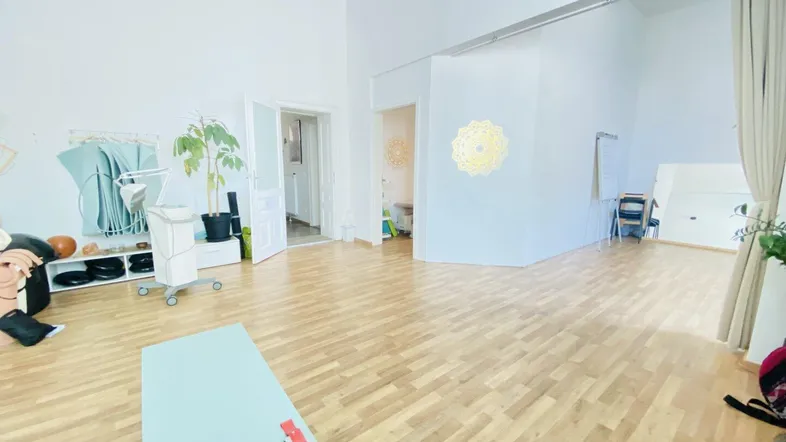 Heller, offener Raum mit Holzboden, hohen Decken und viel Tageslicht, ideal für Kurse oder Therapien.