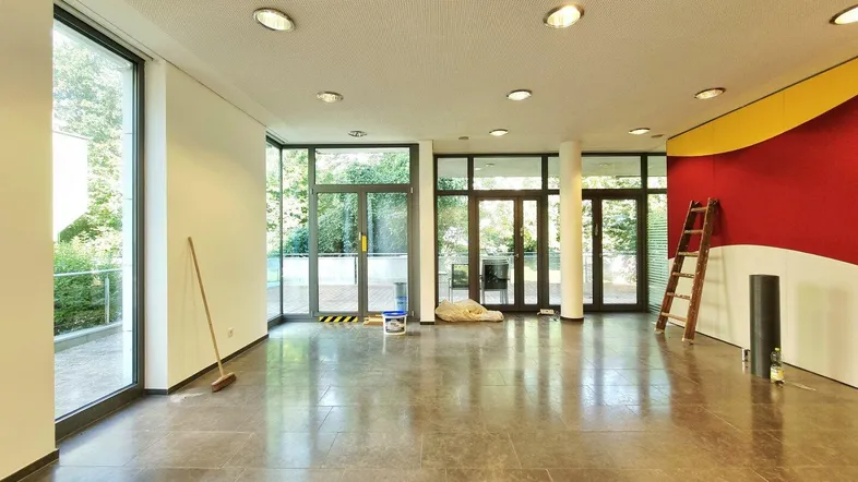 Großer, leerer Gewerberaum mit großen Fenstern und Zugang zum Außenbereich, bereit für die Gestaltung.