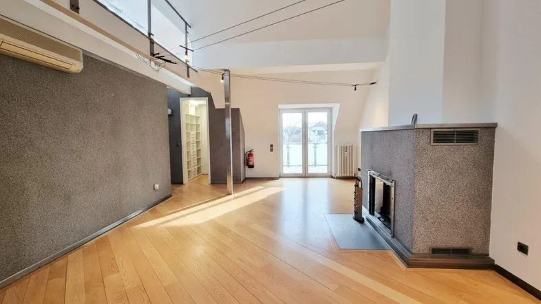 Helles Wohnzimmer mit Holzboden, Kamin und Zugang zu einem Balkon, ideal für entspannte Abende.