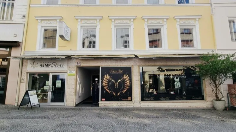 Historisches Gebäude mit gelber Fassade und Geschäften im Erdgeschoss an einer belebten Straße.