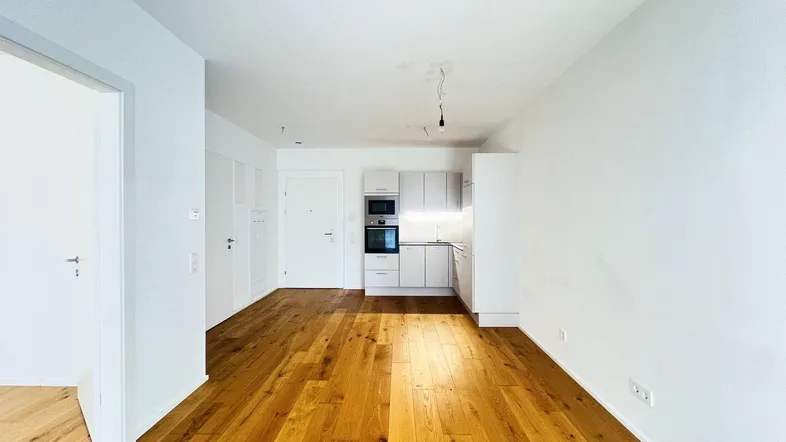 Helles Wohnzimmer mit Holzboden und integrierter Küchenzeile in modernem Design.