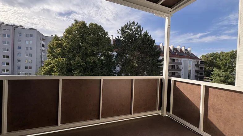 Geräumiger Balkon mit Blick auf die umliegenden Gebäude und viel Grün.