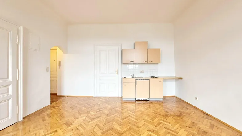 Helles Wohnzimmer mit Fischgrätparkett und integrierter Küchenzeile, ideal für ein Studio-Apartment.