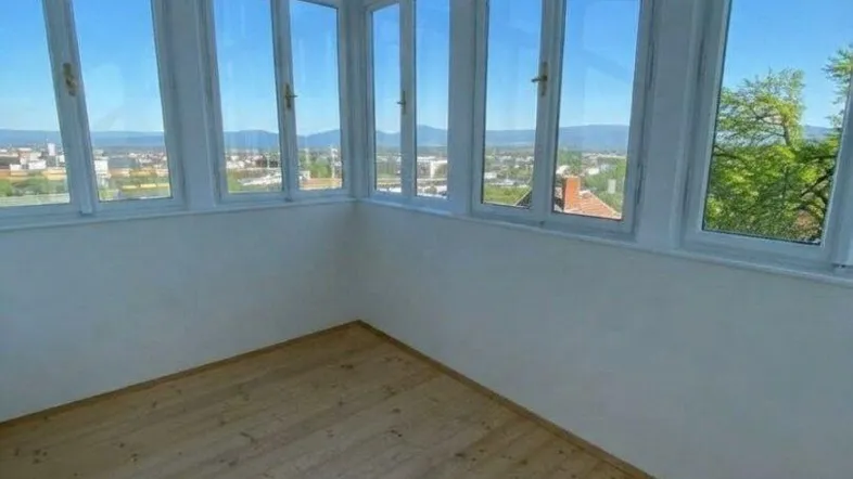 Heller Raum mit vielen Fenstern und Panoramablick über die Stadt und die umliegende Landschaft.