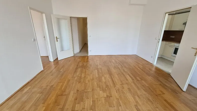Helles, leeres Zimmer mit Parkettboden und weißen Wänden, bereit zur individuellen Gestaltung.