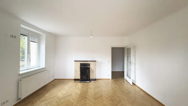 Helles Wohnzimmer mit Fischgrätparkettboden und einem traditionellen Kamin.