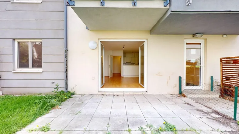 Gepflasterte Terrasse mit Zugang zum Innenbereich der Wohnung und Blick auf den Garten.