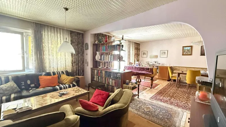 Gemütlicher Wohn- und Essbereich mit traditionellen Möbeln, Teppichen und einem Klavier im Hintergrund.