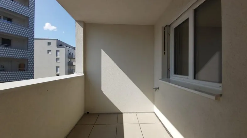 Heller Balkon mit Fliesenboden und Blick auf die umliegenden Gebäude.