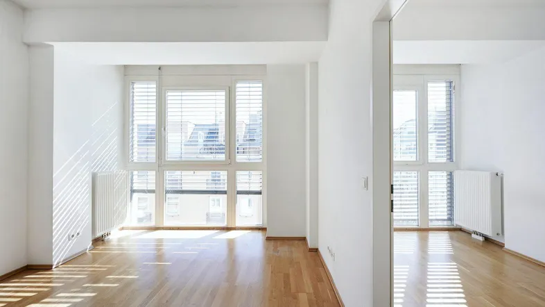 Helles Zimmer mit Parkettboden, großen Fenstern und Heizkörpern, ideal als Wohn- oder Schlafzimmer.