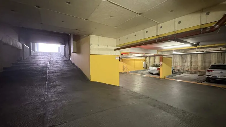 Tiefgarage mit Zufahrtsrampe und mehreren Stellplätzen für Fahrzeuge in gutem Zustand.