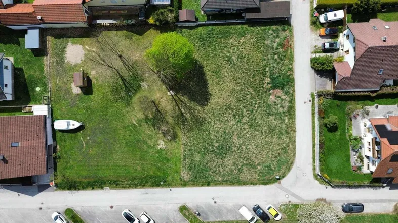 Luftaufnahme eines großen, grünen Grundstücks mit angrenzenden Wohnhäusern und einer Straße.