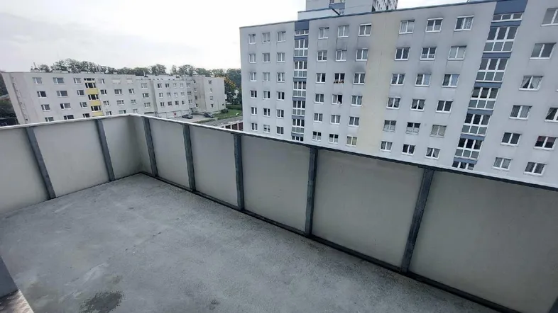 Balkon mit Blick auf umliegende Wohngebäude und grauen Himmel, ideal für entspannte Stunden.