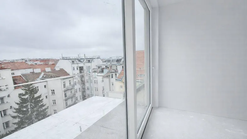Heller Innenraum mit großen Schiebetüren und Blick auf die Stadt, noch im Bau.