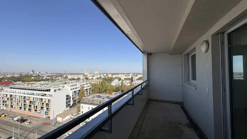 Langer Balkon mit weitreichendem Stadtblick und blauem Himmel.