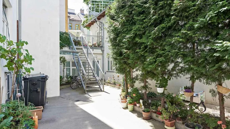 Innenhof mit Pflanzen, Treppenaufgang zu den oberen Etagen und viel Grün.