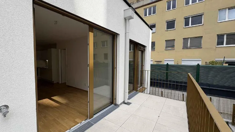Moderne Terrasse mit Fliesenboden und Zugang zu den Innenräumen, umgeben von Stadtgebäuden.