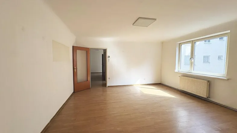 Helles Zimmer mit Laminatboden und Holztür, bereit zur individuellen Gestaltung.