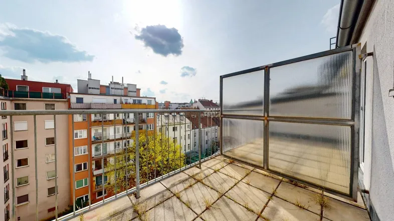 Balkon mit Stadtblick, Betonfliesen und Metallgeländer unter hellem Himmel.