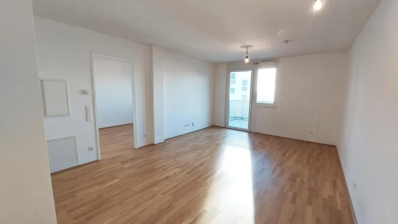 Helles Wohnzimmer mit Parkettboden und Zugang zu einem Balkon, ideal für offenes Wohnen.