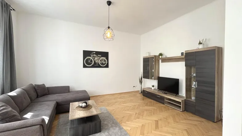 Helles Wohnzimmer mit modernem Ecksofa, Parkettboden und einer stilvollen Medieneinheit.