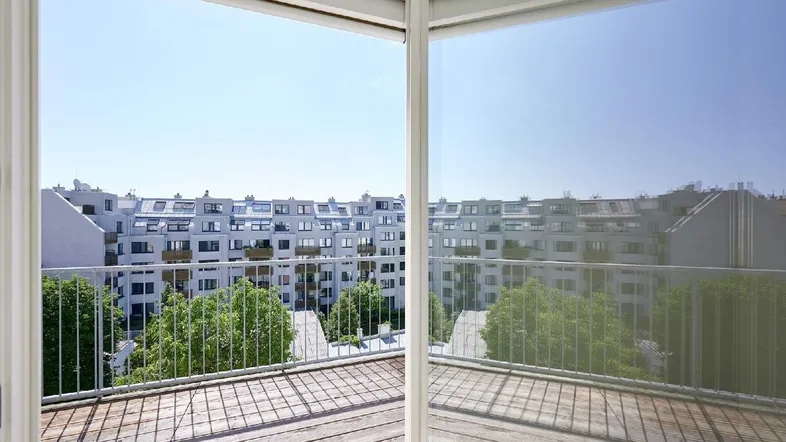 Geräumiger Balkon mit Holzboden und weitem Blick über die umliegenden Gebäude der Stadt.