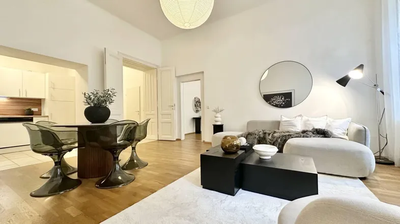 Helles Wohn- und Esszimmer mit Holzboden, modernen Möbeln und offener Küche im Hintergrund.