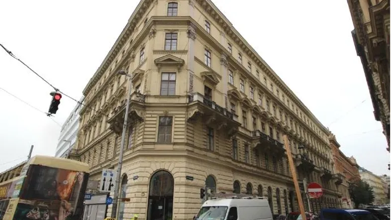 Historisches Eckgebäude mit klassischer Fassade und vielen Fenstern an einer belebten Straße.