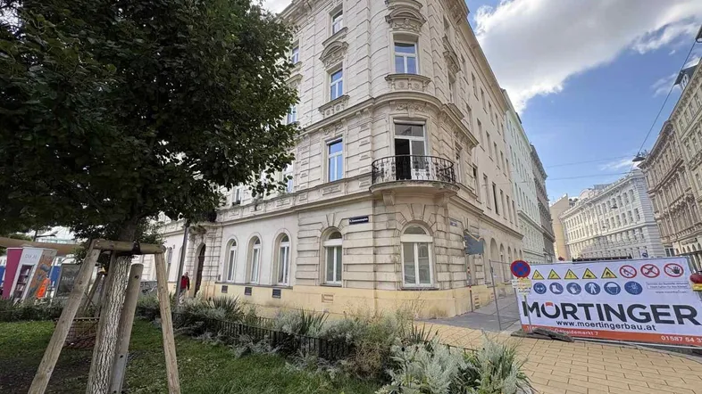 Klassisches Eckgebäude mit historischer Fassade und kleinem Balkon an einer städtischen Straße.